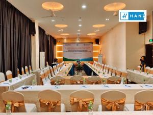 HANZ Premium Bamboo Hotel في مدينة هوشي منه: قاعة اجتماعات مع طاولات وكراسي وشاشة