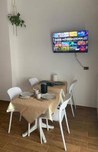 mesa de comedor con sillas blancas y TV en Colle Veralli, en Foce