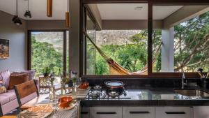 una cucina con bancone, lavandino e alcune finestre di Chalé Aurora da Serra - Lapinha da Serra a Santana do Riacho