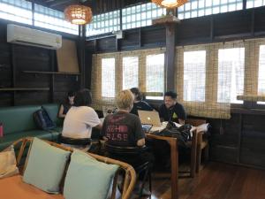 a group of people sitting at a table with laptops at Non House Hostel บ้านนอนโฮสเทล in Bangkok