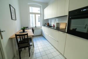 eine Küche mit weißen Schränken, einem Tisch und einem Fenster in der Unterkunft FULL HOUSE Premium Apartments Magdeburg E3 in Magdeburg