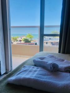 dos toallas sentadas en una cama frente a una ventana en Perequê Praia Hotel, en Porto Belo