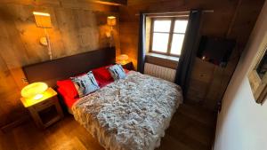 Un dormitorio con una cama con almohadas rojas y una ventana en l’escalade 3, en Courchevel