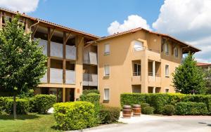 un edificio de apartamentos con arbustos delante de él en Lagrange Vacances Le Clos des Vignes, en Bergerac