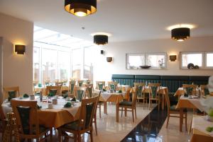 - une salle à manger avec des tables, des chaises et des fenêtres dans l'établissement Apartment Hotel Rüther, à Papenbourg