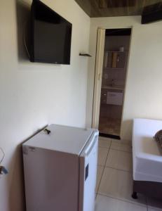 Zimmer mit einem Kühlschrank und einem TV an der Wand in der Unterkunft Pousada Mar e Sol in Saquarema