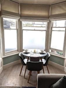 een eetkamer met een tafel en drie ramen bij Beautiful Ground floor apartment with Parking, Exeter in Exeter