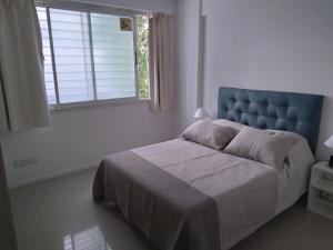 Schlafzimmer mit einem Bett mit blauem Kopfteil und einem Fenster in der Unterkunft STRADA II in Buenos Aires