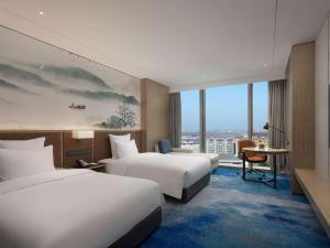 um quarto de hotel com duas camas e uma janela em Pullman Huai'an 淮安铂尔曼酒店 em Huai'an