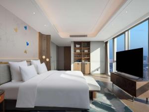 um quarto com uma cama branca e uma televisão de ecrã plano em Pullman Huai'an 淮安铂尔曼酒店 em Huai'an