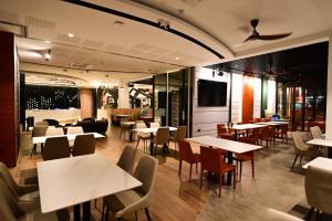 um restaurante com mesas e cadeiras e uma televisão em Rume Hotel em Kuching