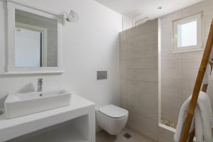 uma casa de banho branca com um lavatório e um WC em Stegna Akti Luxury Suites em Archangelos