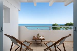 uma varanda com duas cadeiras e uma mesa e o oceano em Stegna Akti Luxury Suites em Archangelos