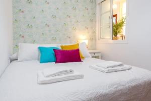 - un lit blanc avec des oreillers colorés dans l'établissement Apartamento FEDUCHY 10 min de la playa 2 baños, à Cadix