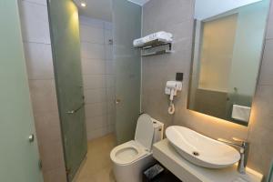 a bathroom with a toilet and a sink at Rume Hotel in Kuching