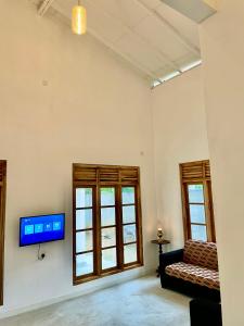 salon z kanapą i telewizorem na ścianie w obiekcie ALOHA Second Home w Tangalli