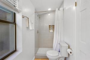 a white bathroom with a toilet and a shower at Wimberley Log Cabins Resort and Suites- Unit 3 in Wimberley +12 photos