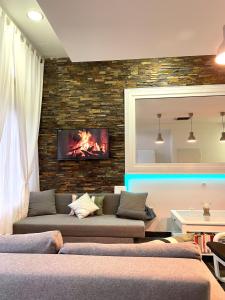 a living room with a couch and a tv on a brick wall at Pepino, Holiday House with a garden in Vrhnika