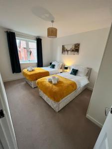 ミルトン・キーンズにある4 Bed spacious property Max 8 Sleepsのベッドルーム1室(オレンジ色の毛布を使用したベッド2台付)