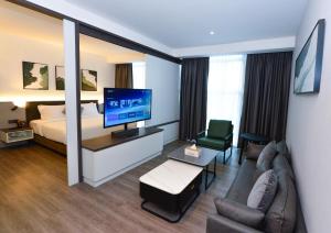 a hotel room with a bed and a couch and a television at Rume Hotel in Kuching