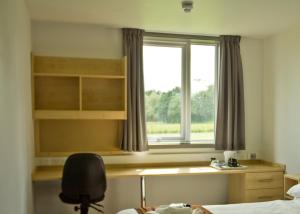 una camera da letto con scrivania e finestra di Keynes College a Canterbury