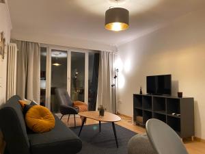 Comfort 1 and 2BDR Apartment close to Zurich Airport في زيورخ: غرفة معيشة مع أريكة وكراسي وتلفزيون