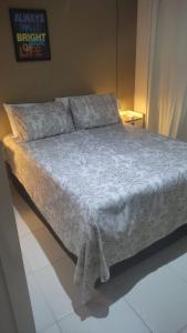 a bedroom with a bed with a white comforter at Flat Quartier - Aldeia das Águas in Barra do Piraí