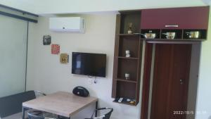 a room with a table and a tv on a wall at Flat Quartier - Aldeia das Águas in Barra do Piraí