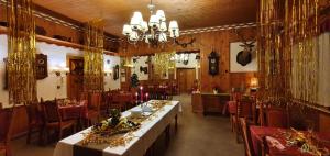 una sala da pranzo con tavoli, sedie e lampadario a braccio di Hotel Lesní dům a Janské Lázně