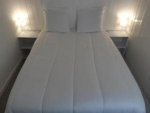 1 cama blanca grande con 2 almohadas y 2 luces en Appartement en station de ski à 700 m des télécabines et 100 m du centre-village en Les Carroz d'Araches