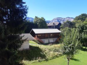 una casa en un campo con montañas en el fondo en Appartement en station de ski à 700 m des télécabines et 100 m du centre-village, en Les Carroz d'Araches