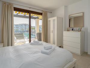Un dormitorio blanco con una cama grande con toallas. en Beautiful Duquesa Harbour apt 2001 en Manilva