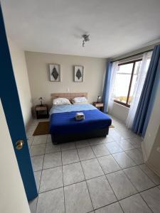 een slaapkamer met een blauw bed en een groot raam bij 3D 2B cerca playa y centro, Park Surf in Iquique