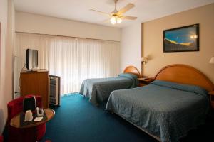 a hotel room with two beds and a flat screen tv at Hotel Playa in San Clemente del Tuyú