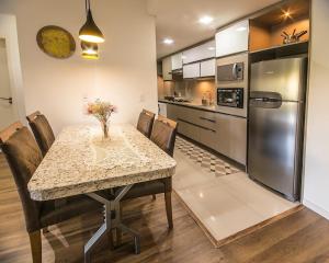 uma cozinha com uma mesa com cadeiras e um frigorífico em Apartamento no cetro Canela em Canela