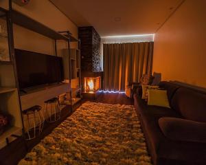uma sala de estar com um sofá, uma televisão e uma lareira em Apartamento no cetro Canela em Canela