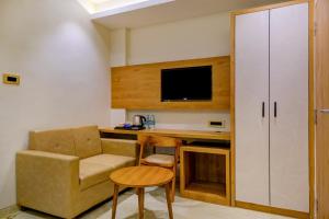 een kamer met een bureau, een stoel en een tv bij Metropolis Business Hotel in Panaji