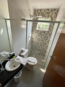 łazienka z toaletą i umywalką w obiekcie Hotel Cajueiro Guarujá w mieście Guarujá
