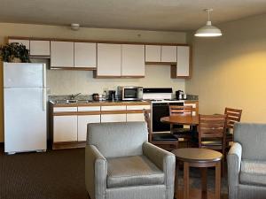 a kitchen with a white refrigerator and a table and chairs at AmericInn by Wyndham Petoskey in Petoskey
