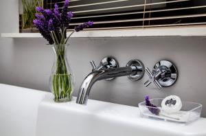 a sink with a vase of purple flowers on it at The Grey House in Beaufort West