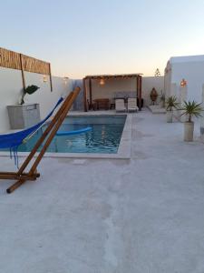a swimming pool with a hammock and a patio at Houche djerbien in Mezraya