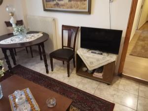 sala de estar con TV, mesa y sillas en Σπίτι στη Γωνία, en Tríkala