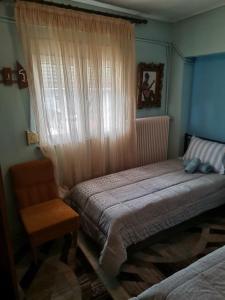 1 dormitorio con 2 camas, silla y ventana en Σπίτι στη Γωνία, en Tríkala