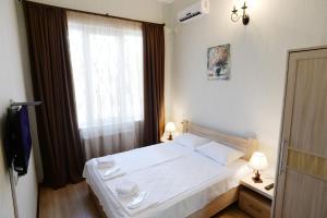 a bedroom with a white bed and a window at Tunti's Apartments in Tbilisi City