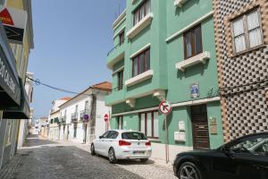 une voiture blanche garée devant un bâtiment vert dans l'établissement Old Town House, à Peniche