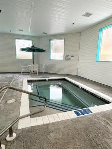 a swimming pool in a building with an umbrella at AmericInn by Wyndham Petoskey in Petoskey