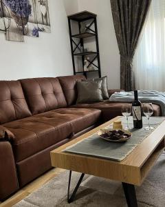 un soggiorno con divano marrone e tavolo con bicchieri da vino di Lavanda a Vršac