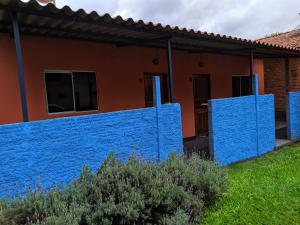 una casa con una pared azul delante de ella en suítes Bomfass en Alto Paraíso de Goiás