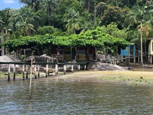 uma casa na costa de um corpo de água em POUSADA CHARMOSA em Superagui