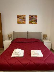 a bedroom with a red bed with two towels on it at EasyRome - Appartamento a Roma San Paolo in Rome
